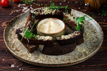 Snack rye croutons with cheese and garlic sauce, garnished with green peas on a plate.