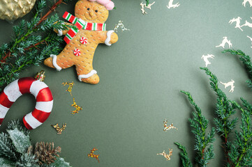 Christmas green background. Fir tree branches, seasonal ornament candy canes, ginger bread man....