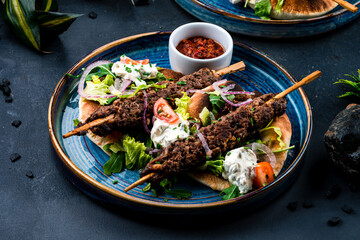 Fresh kebab, barbecued beef on a stick with tomatoes, lettuce, onion, arugula, sour cream, tortilla...