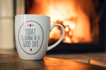 Coffee cup in front of fireplace with saying 