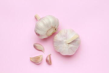 Obraz na płótnie Canvas Fresh white unpeeled head bulb of garlic and garlic cloves on pink color background. Vegan, organic, vitamins. Natural antibiotic, antioxidant, Allicin. Top view. Flat lay
