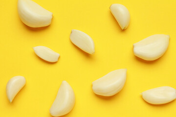 Fresh garlic cloves on yellow color background. Vegan, organic, vitamins. Natural antibiotic, antioxidant, Allicin. Top view. Flat lay