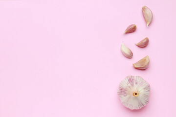 Fresh white unpeeled head bulb of garlic and garlic cloves on pink color background. Vegan, organic, vitamins. Natural antibiotic, antioxidant, Allicin. Top view. Flat lay. Copy space for text