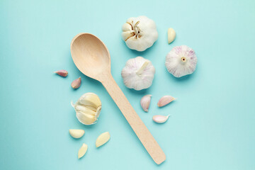 Fresh white unpeeled head bulb of garlic and garlic cloves on blue color background with wooden spoon. Vegan, organic, vitamins. Natural antibiotic, antioxidant, Allicin. Top view. Flat lay