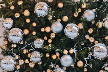 Golden, silver glittering balls and stars adorn the fir branches. Christmas decorations and toys. Festive background.