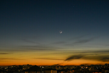 Crescent moon in the city sunset