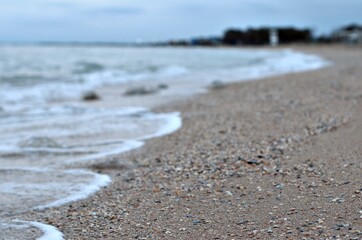Sea wave rolls along the shore of a sandy beach, autumn footage of the seascape, blurred background, selective focus Sea of Azov, Russia