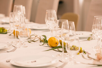 Decorating a festive table. Wedding table decoration with glasses and of natural fresh leaf with lemons