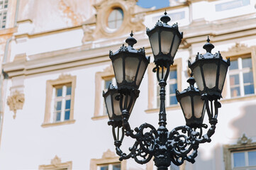 Ornate large old black vintage openwork lantern in the historical center of Lviv against the old building. Winter city concept.