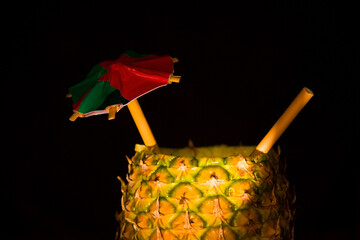 Exotic pineapple in the shape of a drink, with organic straw and mini umbrella