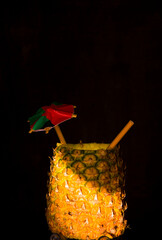 Exotic pineapple in the shape of a drink, with organic straw and mini umbrella