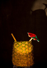 Exotic pineapple in the shape of a drink, with organic straw and mini umbrella