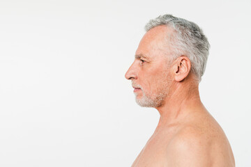 Obraz premium Sideview closeup portrait of caucasian naked shirtless mature elderly senior man with grey hair and beard isolated in white background. Skin care, rejuvenation male beauty concept