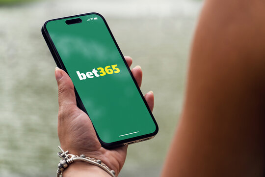 Girl in the park holding a smartphone iPhone 14 Pro with Bet365 betting provider app on the screen. Lake in the background. Rio de Janeiro, RJ, Brazil. November 2022