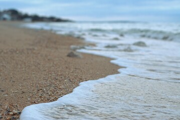 Sea wave rolls along the shore of a sandy beach, autumn footage of the seascape, blurred background, selective focus Sea of Azov, Russia