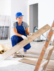 Professional female builder laying laminate flooring in a room being renovated
