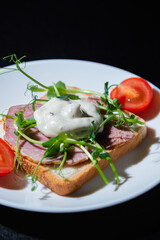 sandwich with bacon and microgreens and tomatoes on a black background