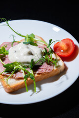 sandwich with bacon and microgreens and tomatoes on a black background