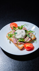 sandwich with bacon and microgreens and tomatoes on a black background