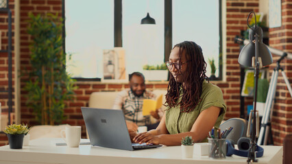 Female freelancer analyzing corporate report on laptop, using online company data to send professional email to manager. Young adult working from home and sitting at desk, web results. Tripod shot.