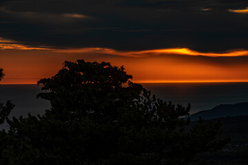 Game of dark and shadow above Brac island, Croatia, with black rain clouds arriving during amazing, orange sunset