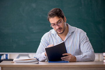 Young male teacher sitting in the classroom