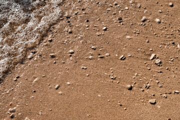 Sand beach full of small stones splashed by gentle adriatic sea waves