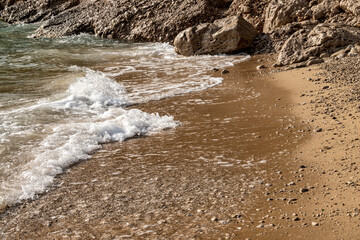 Waves splashing sand beach on Brac island, Croatia creating beautiful, white foam.
