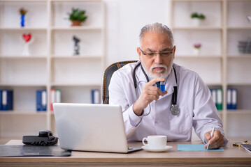 Old male doctor working in the clinic