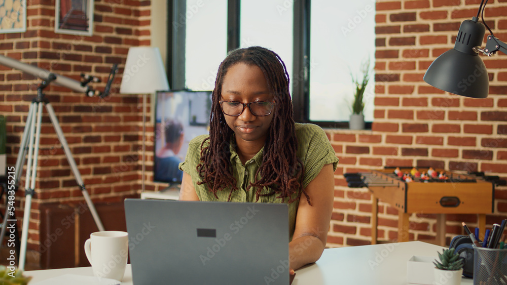 Poster smiling worker browsing internet on laptop at home, working remote to analyze web information for on