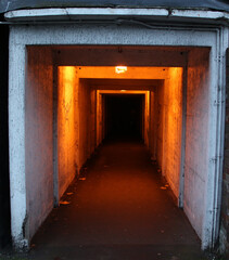 Fototapeta na wymiar Deep tunnel, with viewpoint on other side with yellow light. Dark tunnel in urban. Scary tunnel 