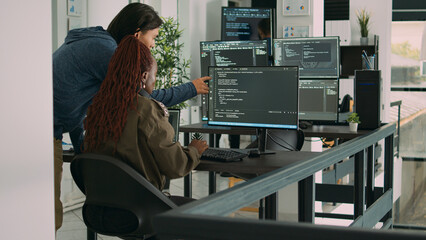 Diverse team of ai cloud programers talking about coding script in front of computer, working on server interface development. Programmers doing teamwork to plan html software language.