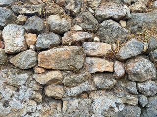 Background, texture, stone wall of round stones cobblestones bricks natural surface natural sharp convex rough stone cobblestone with cracks