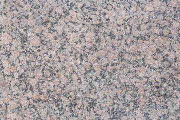 Granite texture. Natural pink granite with a grainy pattern. Stone background. Solid rough surface of rock. Durable construction and decoration material. Close-up.