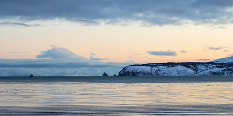 Beautiful panoramic seascape. View of the sea, cape and rocks. Cold weather. Nature of Siberia and the Russian Far East. Travel and tourism in the Magadan region. Gertner Bay, Sea of Okhotsk, Russia.