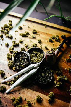 Grinder and joints with marijuana pipe. Drugs and marijuana, marijuana buds. Sativa and indica сbd and tgk on wood. Grass and smoking plants