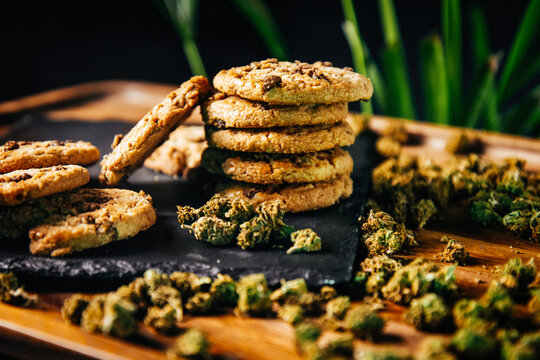 Marijuana cookies, drugs in food, thc and cbd brownies. Drugs and marijuana buds on a plank against the background of growths.