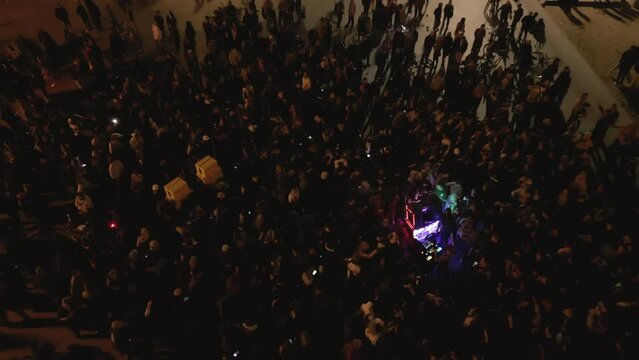 Aerial drone shot above crowd at open-air concert at night on the coast