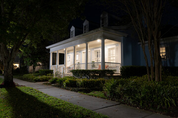 Beautiful Colonial Revival style house with illuminated front porch at night in a suburban...