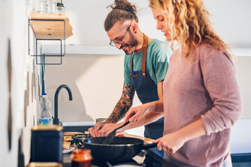 Young couple making breakfast together in the kitchen at home