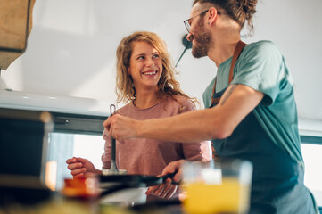 Young couple making breakfast together in the kitchen at home