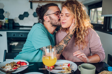 Couple eating breakfast together while sitting at table at home