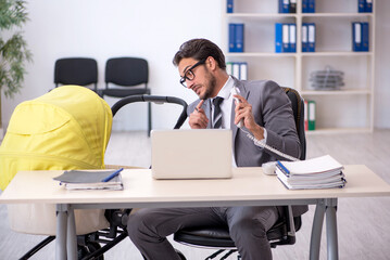 Young male employee looking after new born at workplace