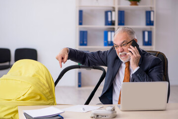 Old male employee looking after new born at workplace