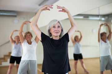 Fototapeta na wymiar Aged women performing ballet dance during their group training in fitness room.