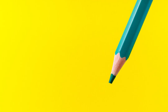 Colored pencil close-up with selective focus on the stylus and a blurred yellow background. Copy space