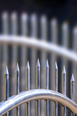 Close up of stainless steel spike gate fence with blurred background in vertical frame