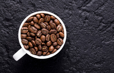Roasted coffee beans in a cup, on dark background, close-up image, space for text