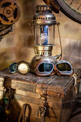 Plakat A compass, a pair of motorcycle goggles, and an old lamp on a trunk. 