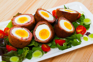 Scottish cuisine. Hard-boiled eggs wrapped in sausage meat, breaded and fried (Scotch eggs) served with mix of greens and cherry tomatoes